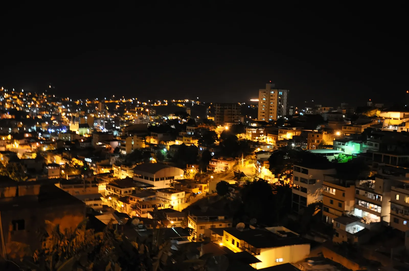 Cachoeiro de Itapemirim à noite, vista do alto: casas e prédios do morro com as luzes acesas